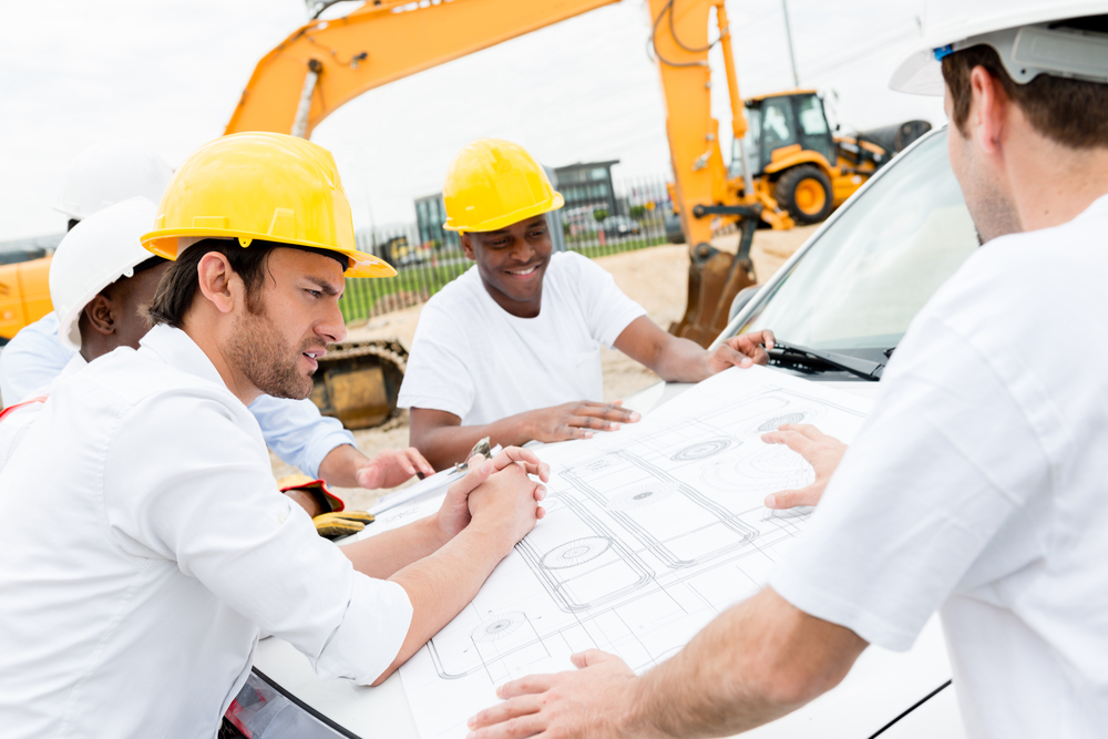 Group of civil engineers working on a construction and looking at blueprints-1
