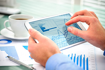 hands with tablet displaying financial charts