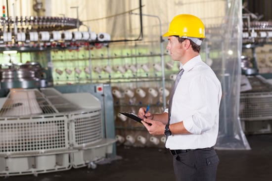 Manufacturing employee writing on a clipboard on the assembly floor